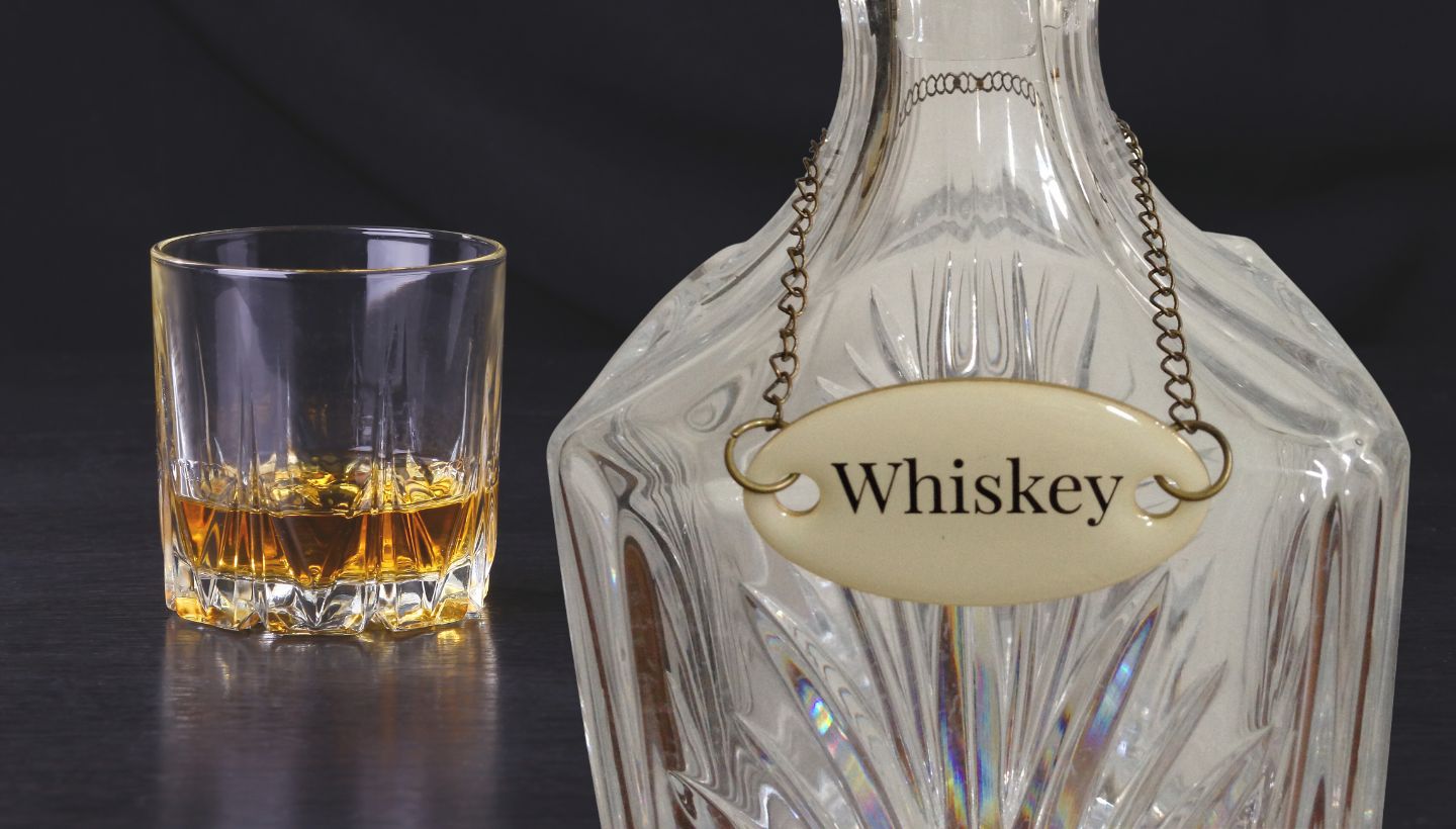 Duke Baron liquor tag on a crystal decanter and a glass of whiskey