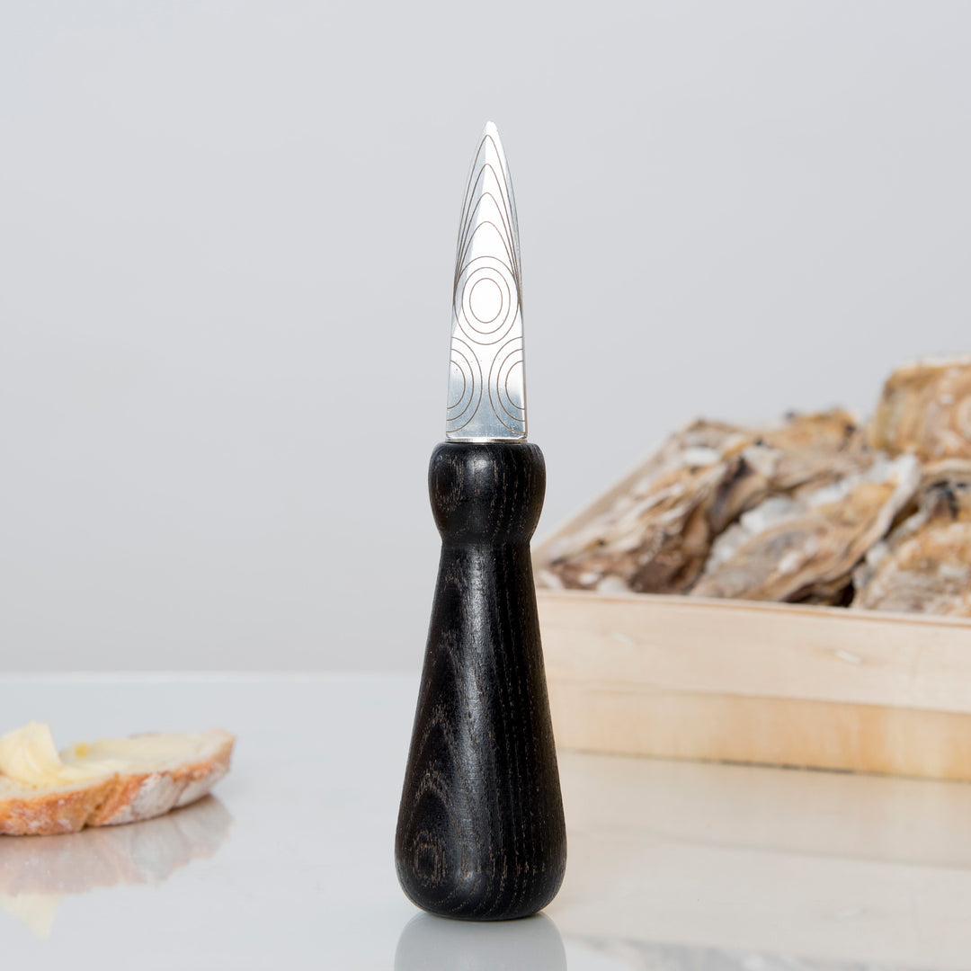 LIB Editeur d'idées FREHEL Laser Engraved Oyster Knife with Ash Wood Grip, Shown with Black Handle and Plate of Oysters