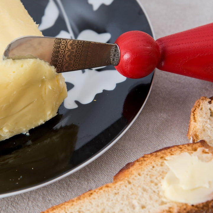 LIB Editeur d'idées NORWELL Butter Knife with engraved blade Made in France shown with red handle in butter showing engraving